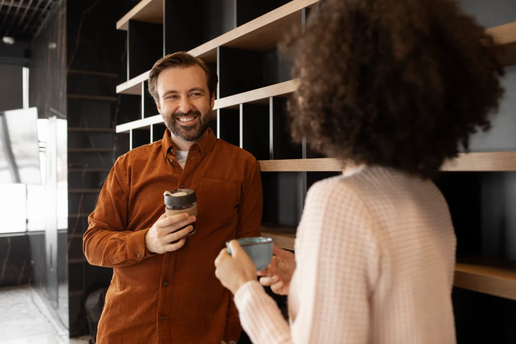 Dois colegas de trabalho conversam durante uma pausa para o café em um ambiente corporativo moderno