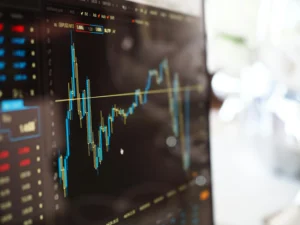 Tela de computador exibindo gráfico de análise financeira com linhas de candlestick e indicadores de mercado, representando dados de variação de preços em tempo real.