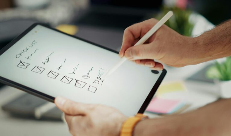 Pessoa usando uma caneta digital em um tablet para marcar itens em uma checklist, representando organização, planejamento e produtividade no trabalho.
