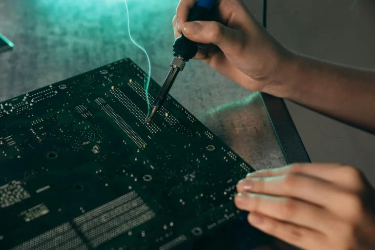 Técnico realizando manutenção em placa eletrônica com ferro de solda, ilustrando processos de gestão de ativos de TI e manutenção