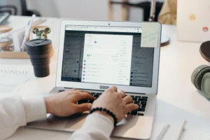 Pessoa trabalhando em um notebook, com as mãos sobre o teclado, utilizando uma plataforma de gerenciamento de tarefas