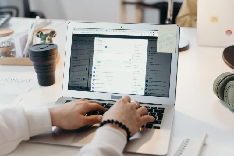 Pessoa trabalhando em um notebook, com as mãos sobre o teclado, utilizando uma plataforma de gerenciamento de tarefas
